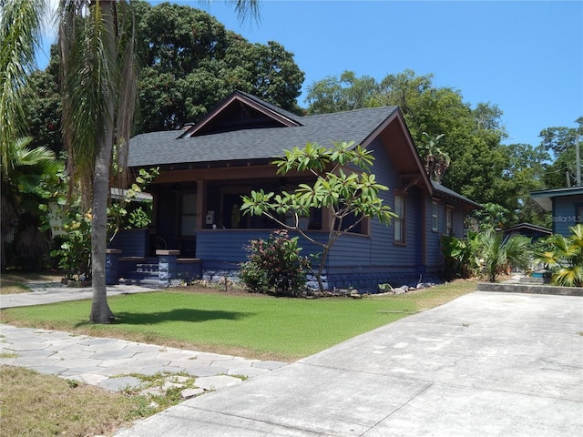 view of front of house with a front lawn and roof with shingles