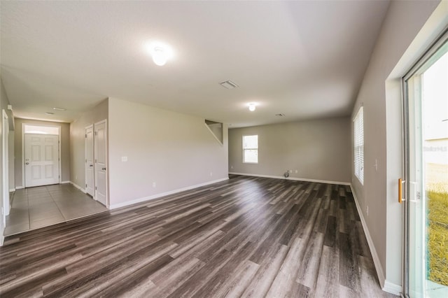 unfurnished room featuring dark wood-type flooring and a healthy amount of sunlight