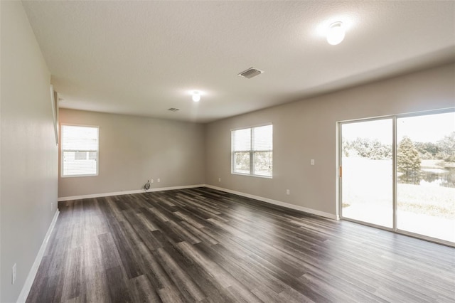 spare room with a textured ceiling and dark hardwood / wood-style flooring