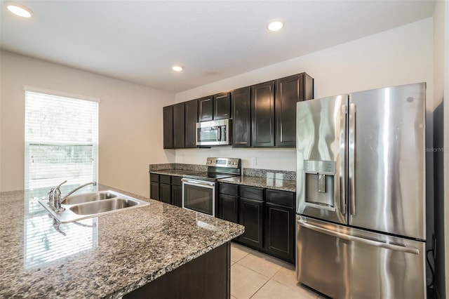 kitchen with dark stone countertops, appliances with stainless steel finishes, sink, and light tile patterned flooring