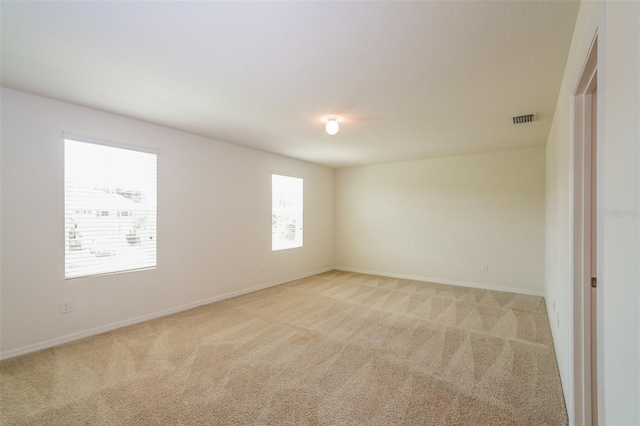 spare room with light colored carpet and a wealth of natural light