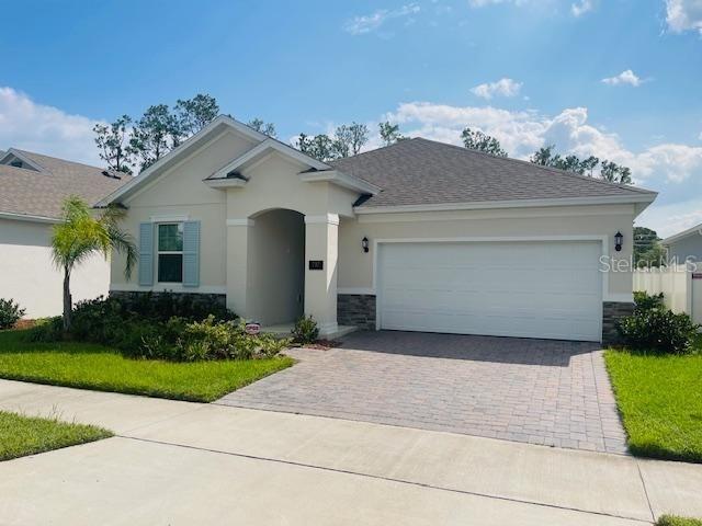 737 Trillium Ct, Debary, FL 32713 - ranch-style home with stone siding, a garage, stucco siding, driveway, and roof with shingles