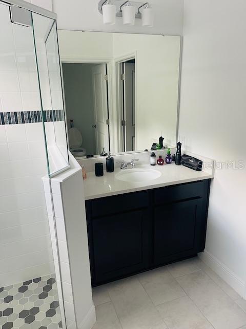 bathroom with vanity, tile patterned flooring, and a tile shower