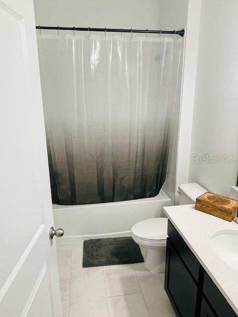 full bathroom with shower / tub combo, vanity, tile patterned flooring, and toilet