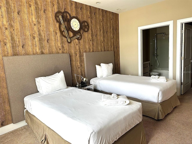 carpeted bedroom with wooden walls and connected bathroom