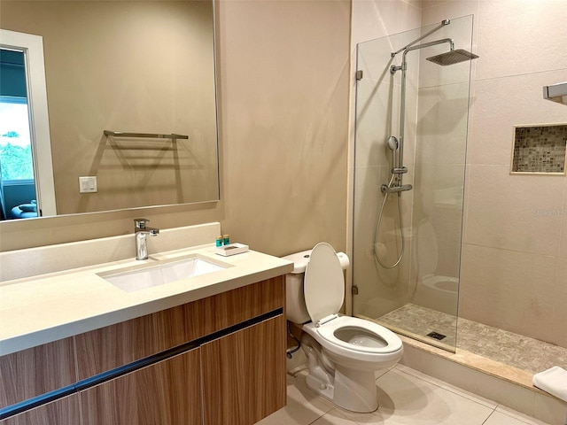 bathroom featuring vanity, toilet, tiled shower, and tile patterned floors