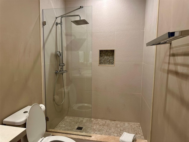 bathroom with tiled shower, toilet, and vanity