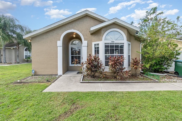 view of exterior entry featuring a lawn and stucco siding