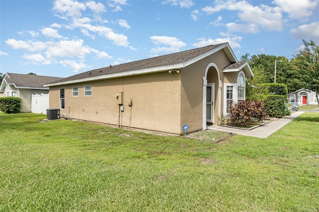 view of side of property featuring central air condition unit, a yard, and stucco siding