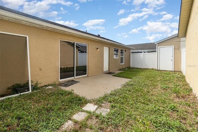 back of house featuring a yard, fence, stucco siding, and a patio