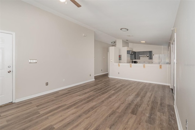 unfurnished living room with baseboards, vaulted ceiling, and wood finished floors