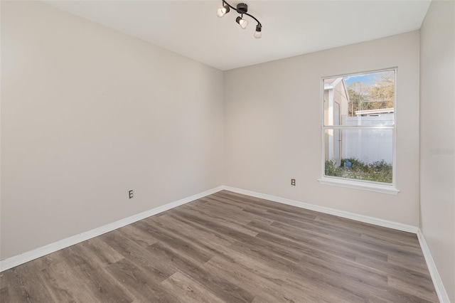 unfurnished room with baseboards and wood finished floors