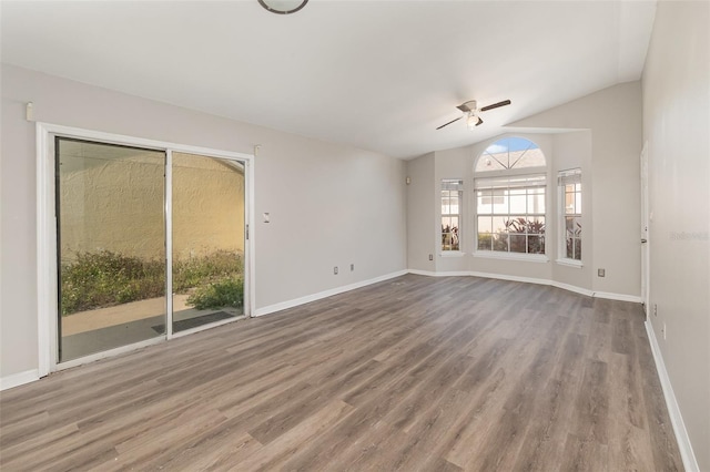 unfurnished living room featuring vaulted ceiling, wood finished floors, and baseboards