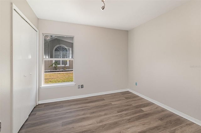 empty room with baseboards and dark wood-style flooring