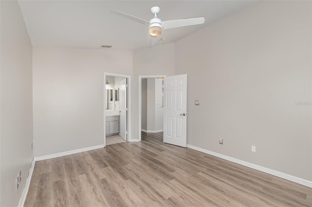 unfurnished bedroom with ensuite bathroom, a ceiling fan, baseboards, vaulted ceiling, and light wood finished floors