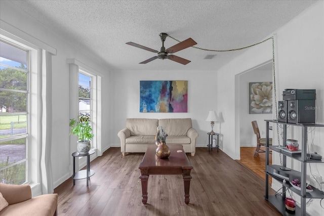 living room featuring a textured ceiling, ceiling fan, and dark hardwood / wood-style floors