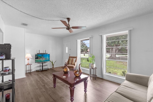 living room featuring dark hardwood / wood-style flooring, ceiling fan, and a textured ceiling