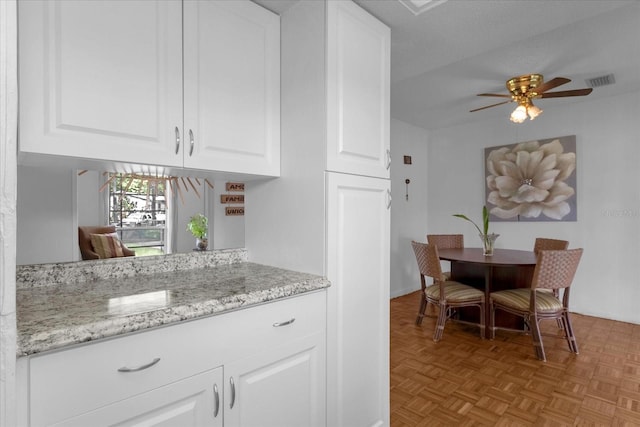 kitchen with white cabinets, light parquet flooring, a textured ceiling, and ceiling fan