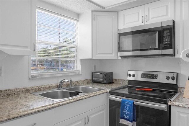 kitchen featuring white cabinets, appliances with stainless steel finishes, a wealth of natural light, and sink