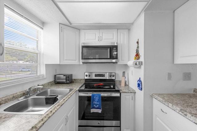 kitchen with stainless steel appliances, a textured ceiling, white cabinetry, and sink