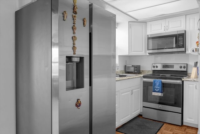 kitchen featuring appliances with stainless steel finishes, white cabinetry, light stone countertops, and light parquet flooring