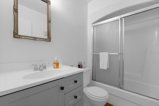 full bathroom with enclosed tub / shower combo, toilet, and vanity