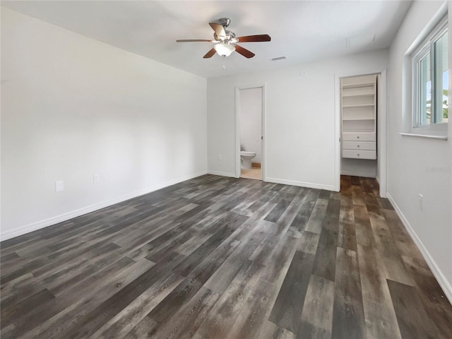 unfurnished bedroom with ensuite bathroom, dark hardwood / wood-style flooring, a closet, a spacious closet, and ceiling fan