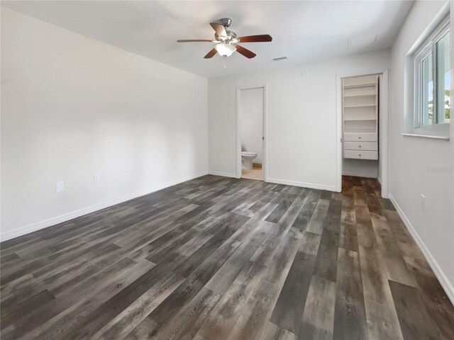 unfurnished bedroom featuring baseboards, visible vents, dark wood-style floors, a spacious closet, and a closet