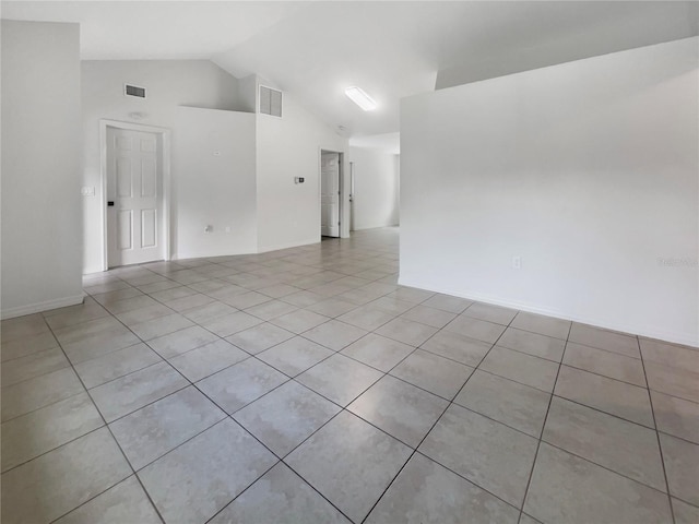 empty room with light tile patterned floors, visible vents, and high vaulted ceiling