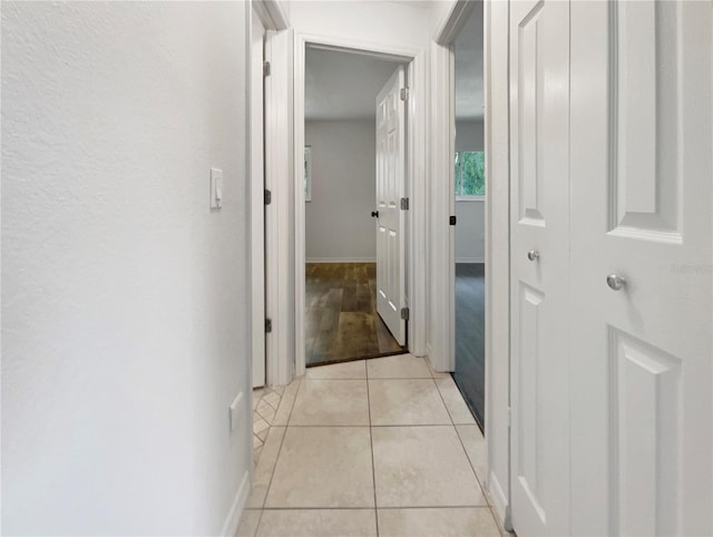 hall featuring light tile patterned floors and baseboards