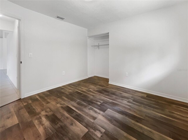 unfurnished bedroom with dark wood-type flooring and a closet