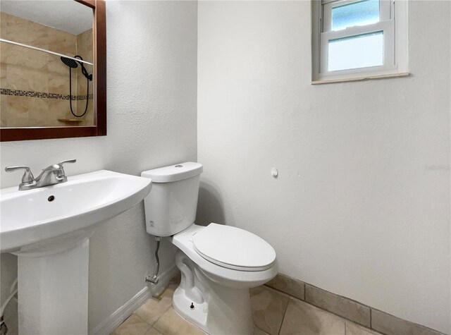 bathroom featuring toilet, tile patterned flooring, baseboards, and walk in shower