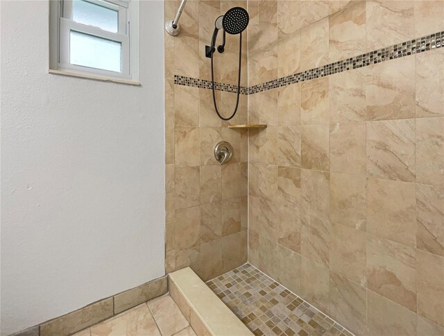 bathroom with tiled shower and tile patterned flooring