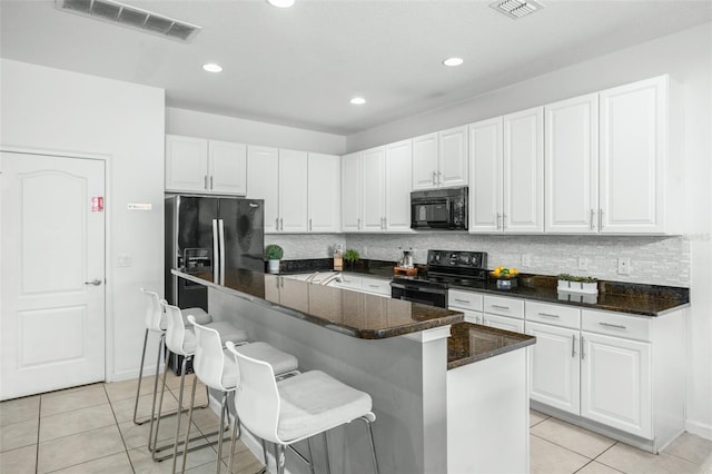kitchen featuring visible vents, white cabinetry, and black appliances
