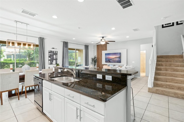 kitchen with visible vents, a center island with sink, a sink, black dishwasher, and light tile patterned flooring