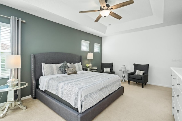 bedroom with light carpet, a raised ceiling, and ceiling fan