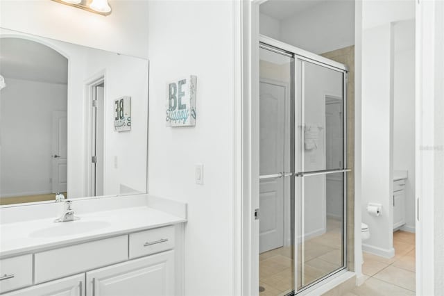 bathroom with vanity, toilet, an enclosed shower, and tile patterned flooring