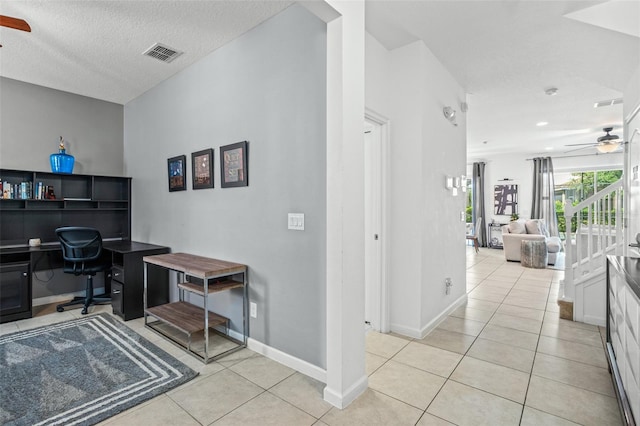 office featuring built in desk, a textured ceiling, a ceiling fan, light tile patterned floors, and visible vents