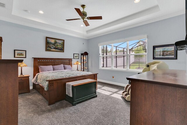 carpeted bedroom with a tray ceiling and ceiling fan