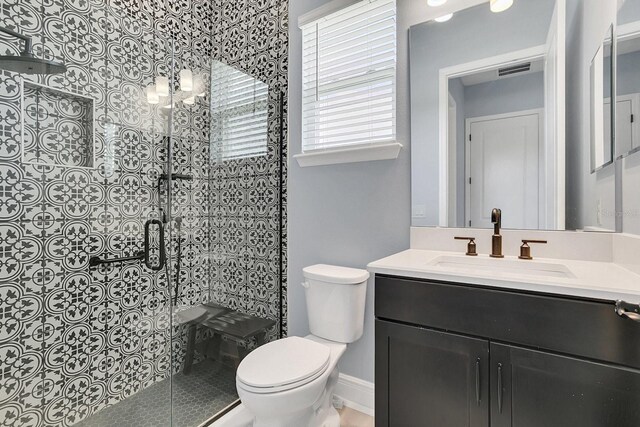 bathroom featuring vanity, toilet, and a shower with door