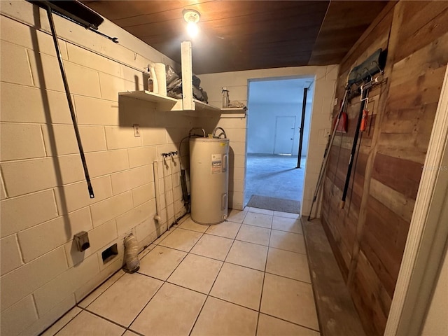 clothes washing area featuring wood ceiling, water heater, and light tile patterned floors