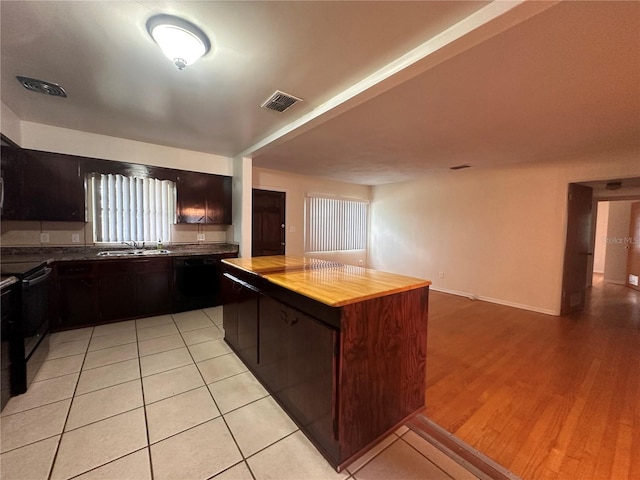 kitchen featuring light wood-type flooring, black appliances, wood counters, and sink