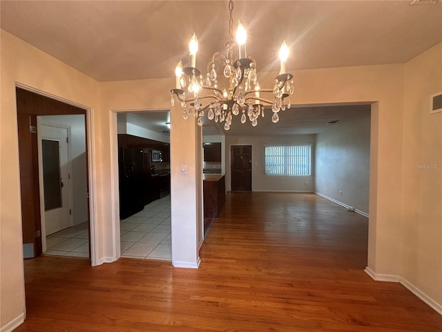 unfurnished dining area featuring hardwood / wood-style flooring and an inviting chandelier