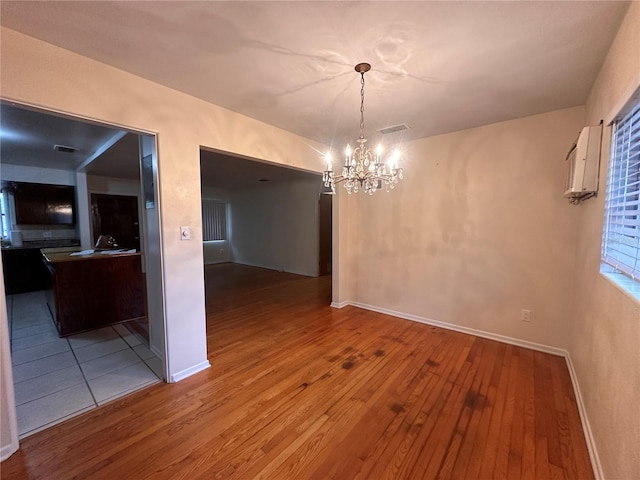 unfurnished dining area with an inviting chandelier and hardwood / wood-style flooring