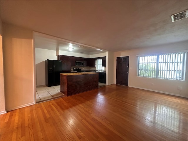 kitchen with kitchen peninsula, stainless steel appliances, light wood-type flooring, and dark brown cabinets