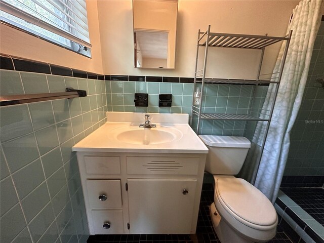 bathroom with vanity, toilet, walk in shower, and tile walls