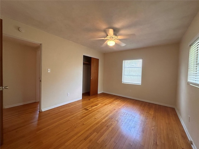 unfurnished bedroom with light wood-type flooring, multiple windows, ceiling fan, and a closet