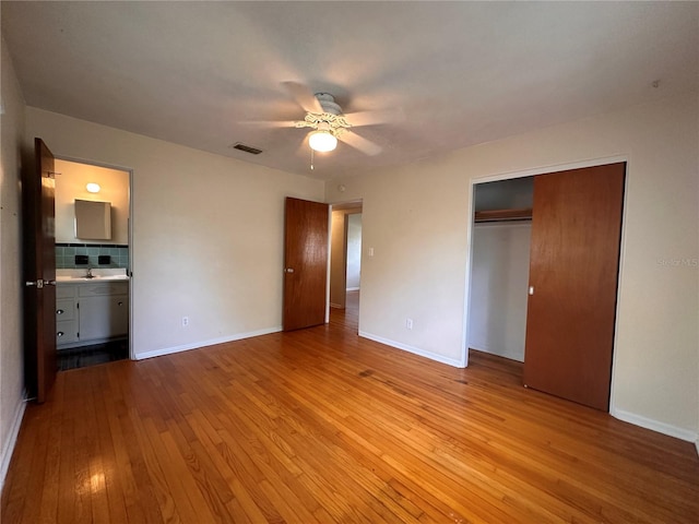 unfurnished bedroom featuring light hardwood / wood-style flooring, sink, ceiling fan, a closet, and ensuite bathroom