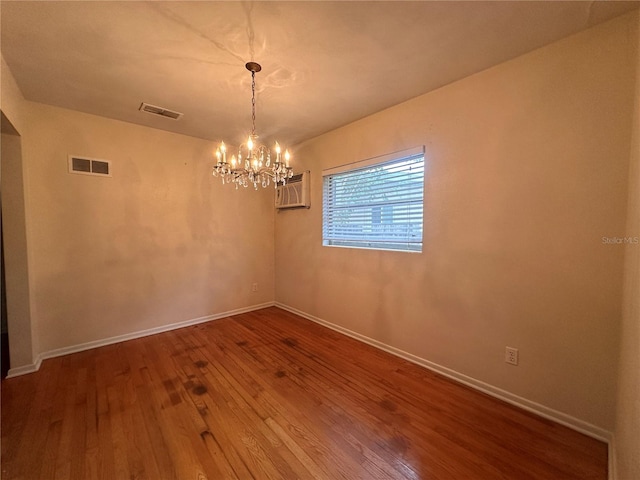 empty room with a chandelier, hardwood / wood-style floors, and an AC wall unit