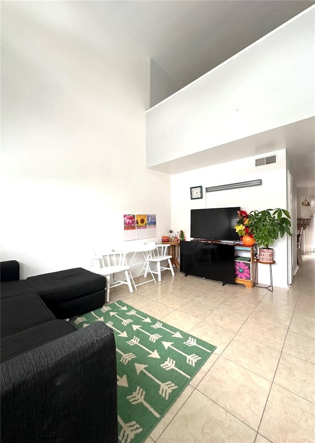 living room featuring light tile patterned floors, visible vents, and a high ceiling